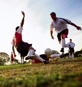 Soccer players tackling for ball